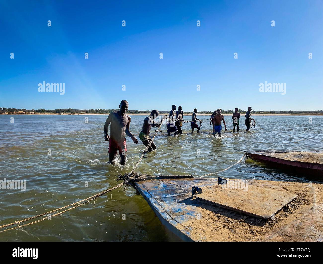 Madagascar, Tsiribihina river, young men tow barge on river Stock Photo
