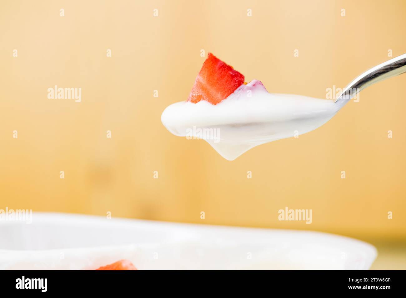 healthy strawberry and white yogurt on the spoon on golden background, concept of healthy food nutrition Stock Photo