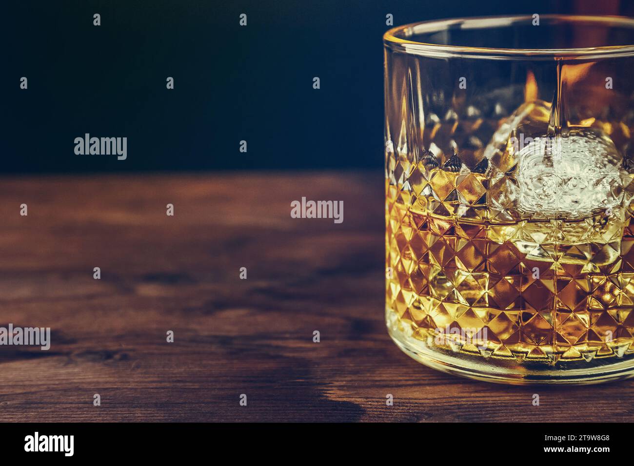 glass of whiskey with ice cubes on wood table, warm atmosphere, time of relax with whisky Stock Photo