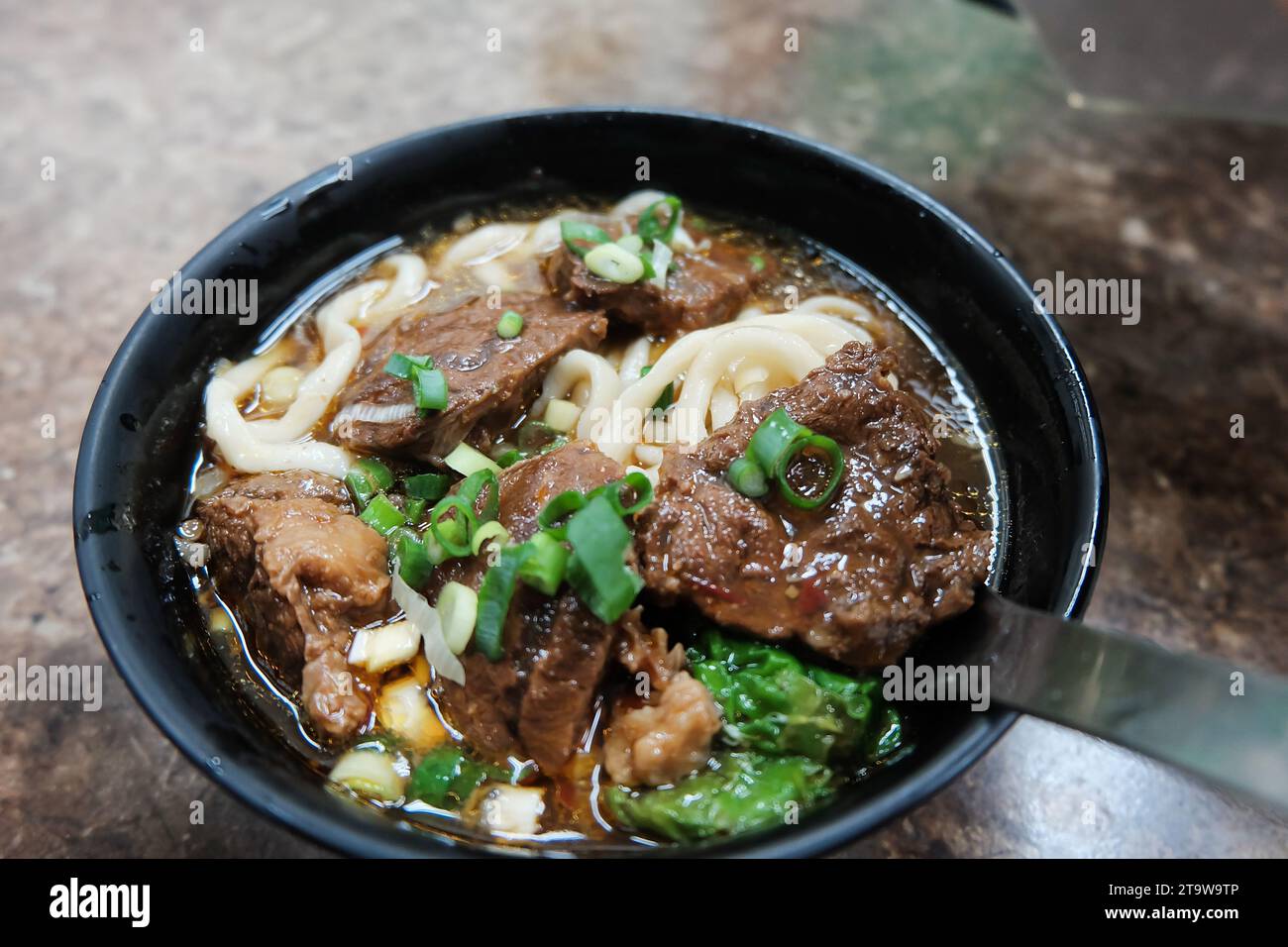 Beef noodles chili sauce served in a bowl on table top view of taiwanese food. Soup beef noodle in a bowl on wooden table. Chinese taiwanese cuisine Stock Photo