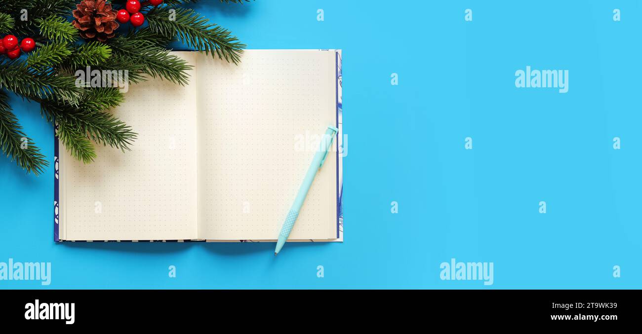 Open notebook with pen on a blue background, spruce branch, top view, empty space. Copy space. Christmas branch and diary for notes Stock Photo