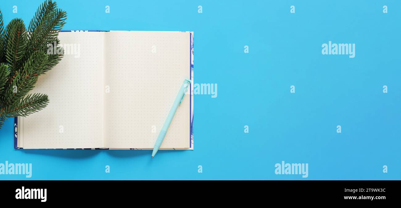 Open notebook with pen on a blue background, spruce branch, top view, empty space. Copy space. Christmas branch and diary for notes Stock Photo