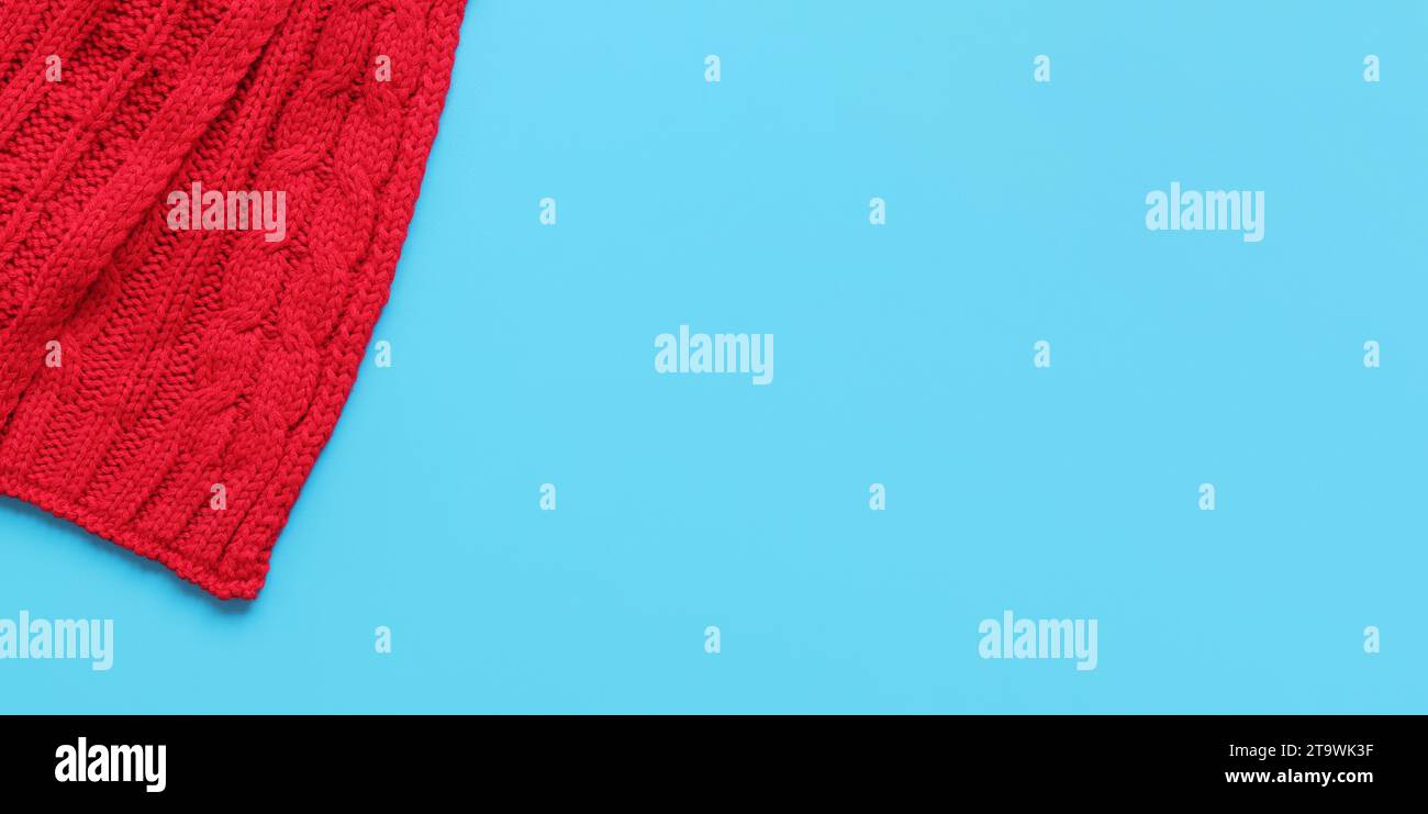 Red knitted scarf on a blue background, top view, copy space. Christmas scarf, clothing, accessory Stock Photo