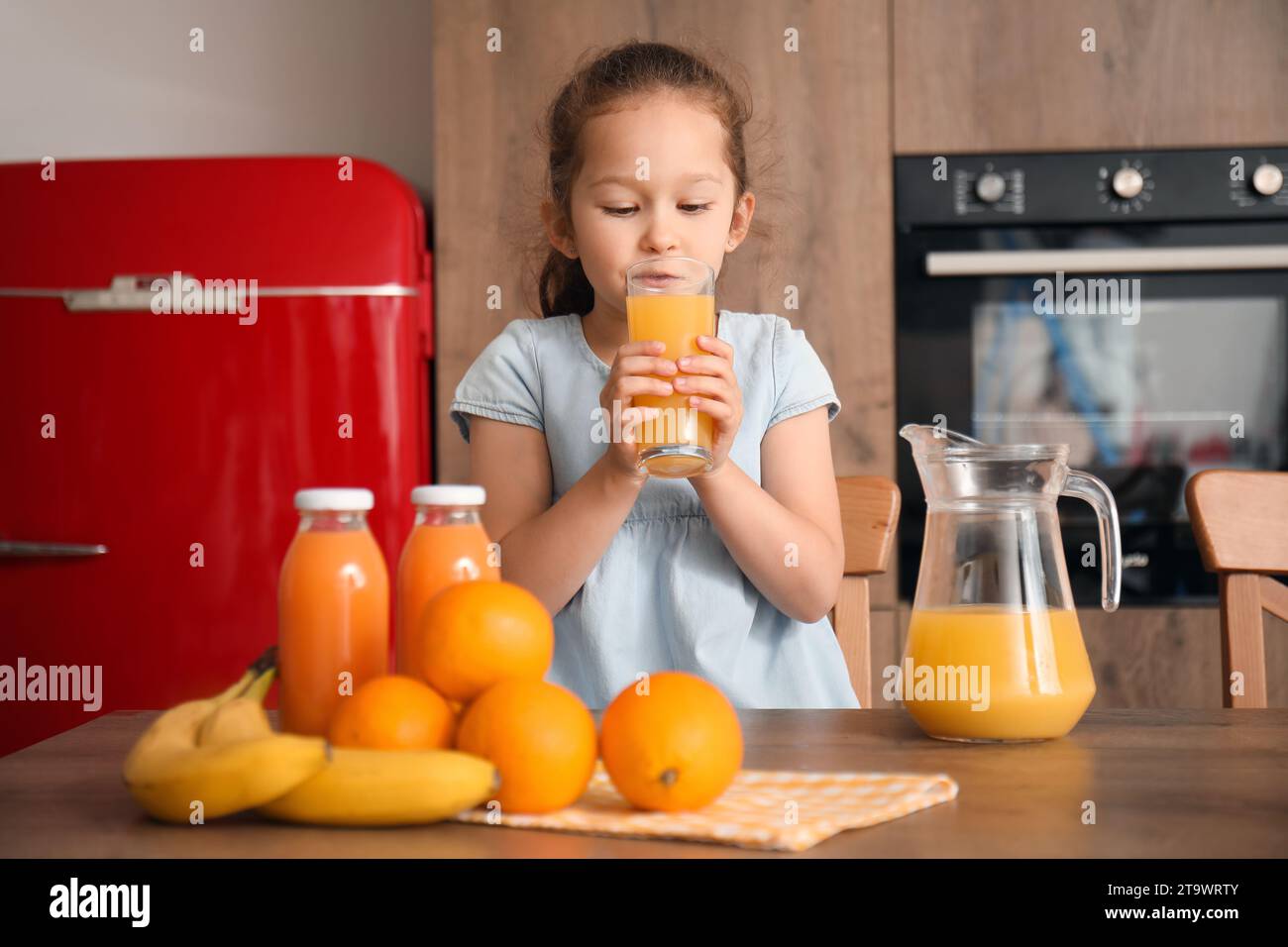 Little girl drinking orange juice in kitchen Stock Photo - Alamy