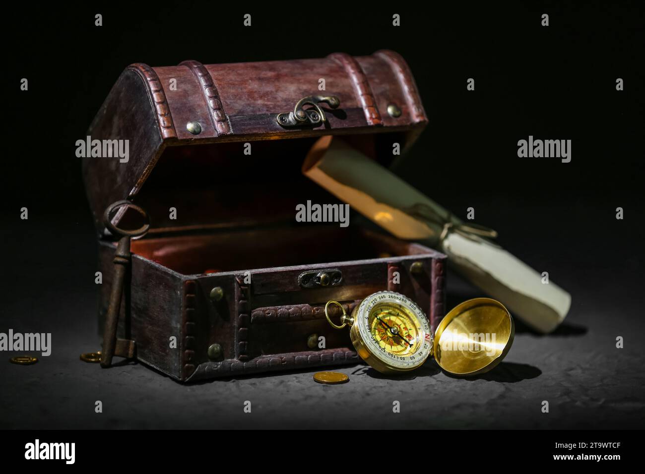 Old chest with treasures, key, scroll and compass on grunge black