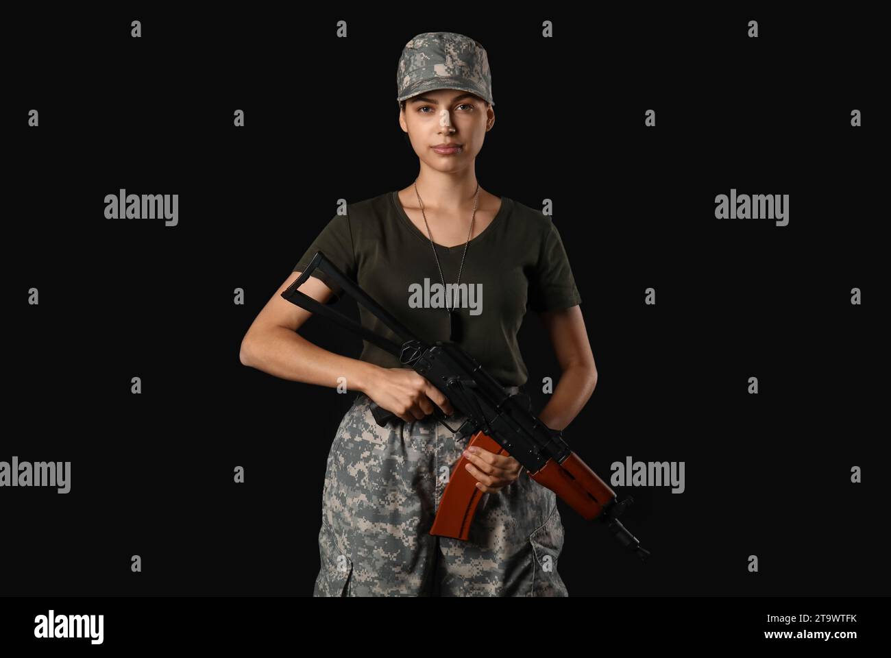 Confident young female soldier with assault rifle on black background ...
