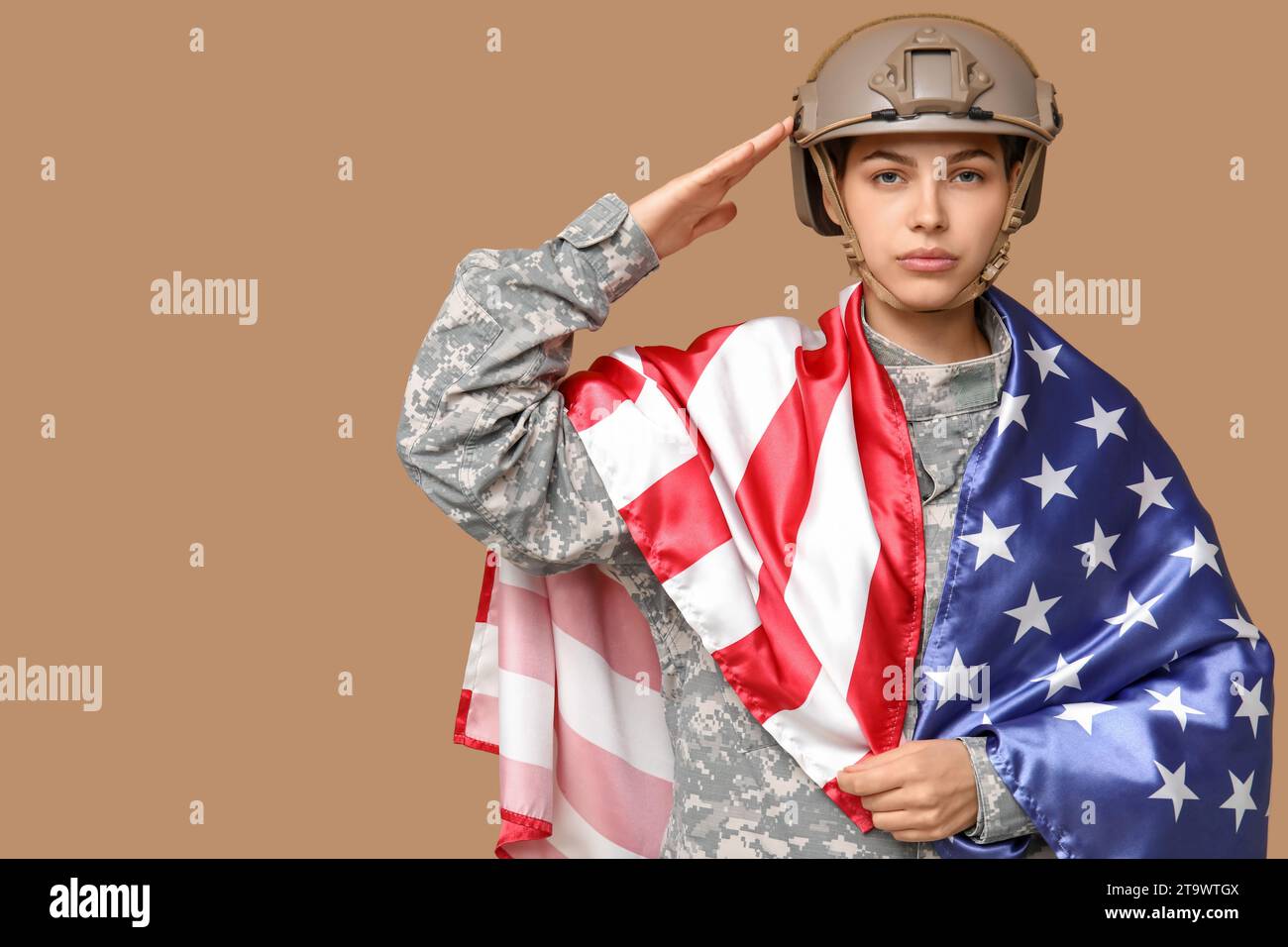 Young female soldier in uniform with flag of USA saluting on beige ...
