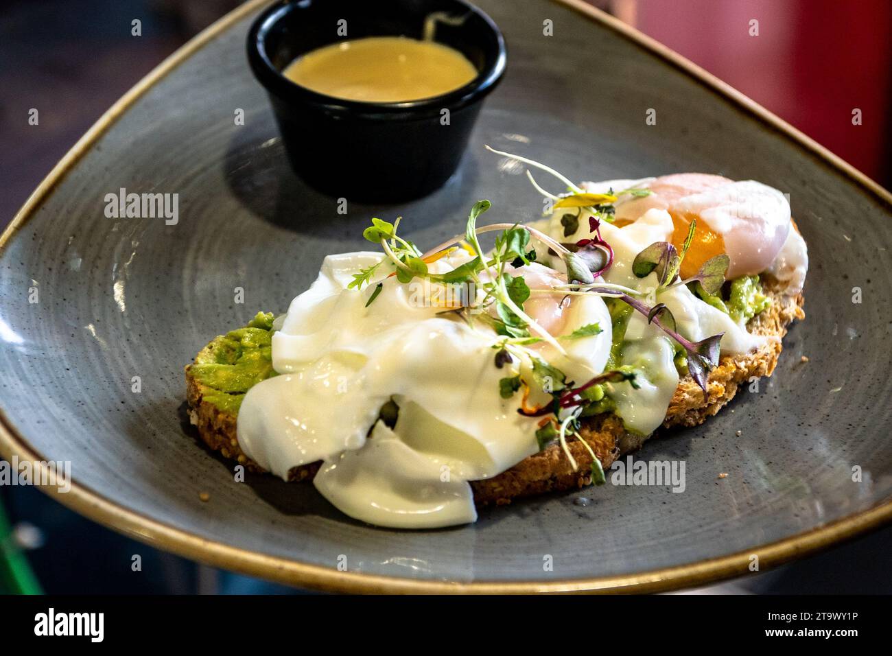 a-slice-of-avocado-toast-topped-with-poached-eggs-and-hollandaise-sauce