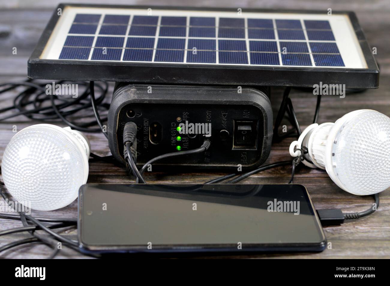 A multi purpose battery charged with a solar panel, a device that converts sunlight into electricity by using photovoltaic (PV) cells, with charging c Stock Photo
