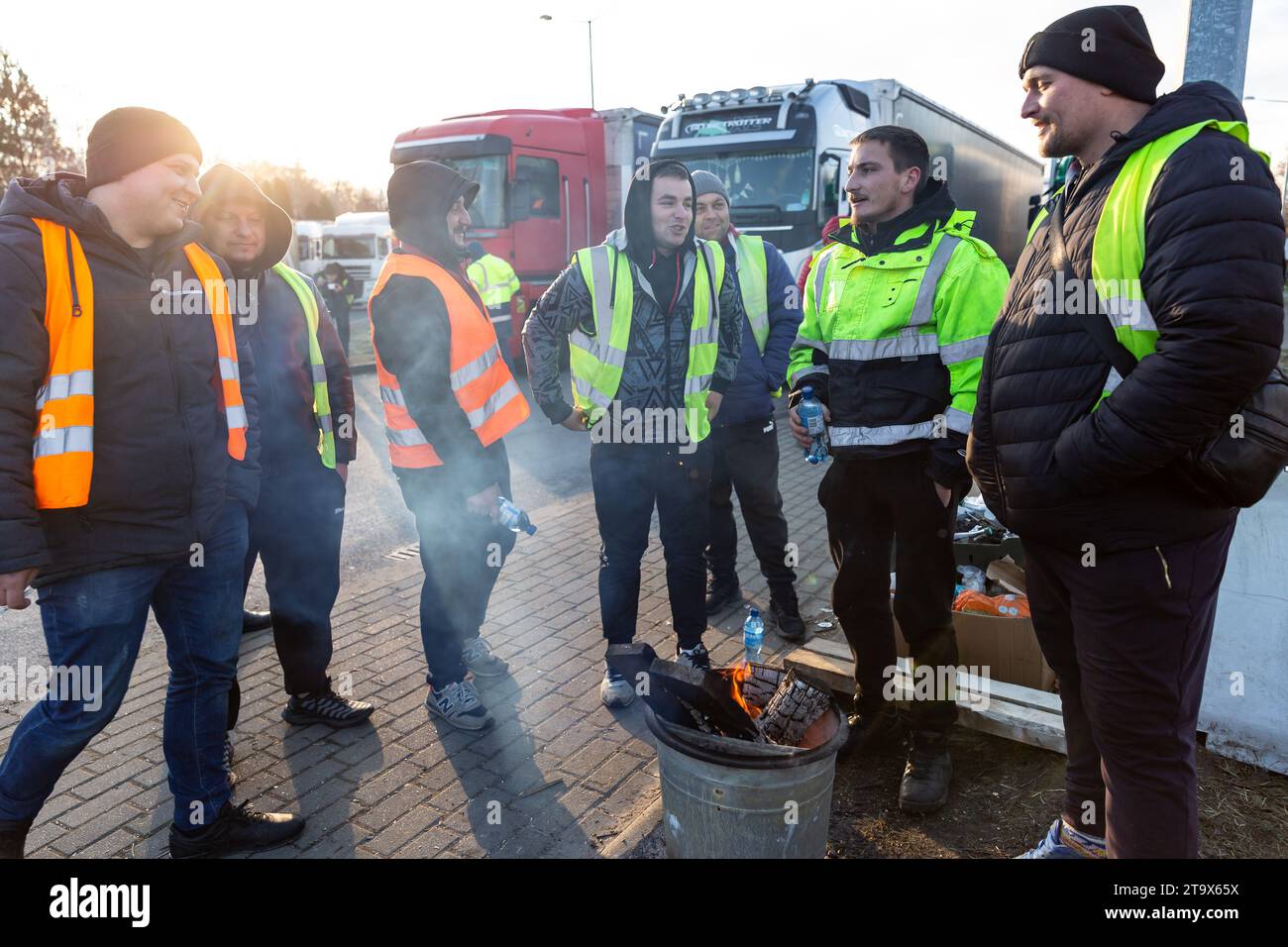 Ukrainian truck drivers stand by a bonfire at a parking place as they wait in a queue to cross the border in Korczowa as Polish transport Union strike and block truck transport in Korczowa - border crossing between Poland and Ukraine on November 27, 2023. The Union demands renegotiation of transport deals between Ukraine and the European Union. Medyka is the fourth strike sites. Protesters allow only 4 commercial trucks per an hour, that excludes humanitarian and military aid and fuel and food. The strike started on November 6. Ukrainian truck drivers say they wait in the queue more than 10 da Stock Photo