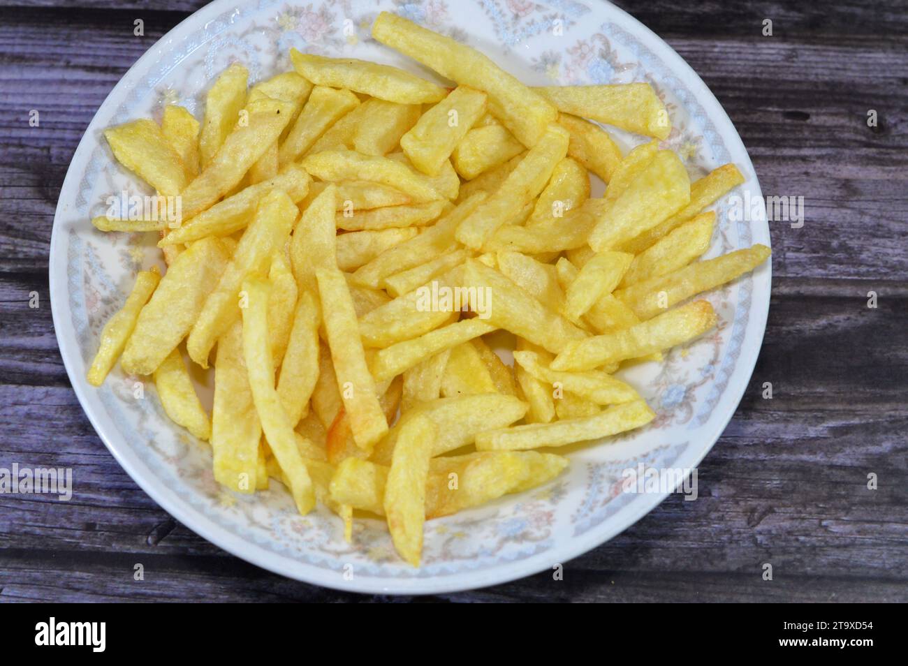 A plate of French fries potatoes fried in boiling hot oil in a deep