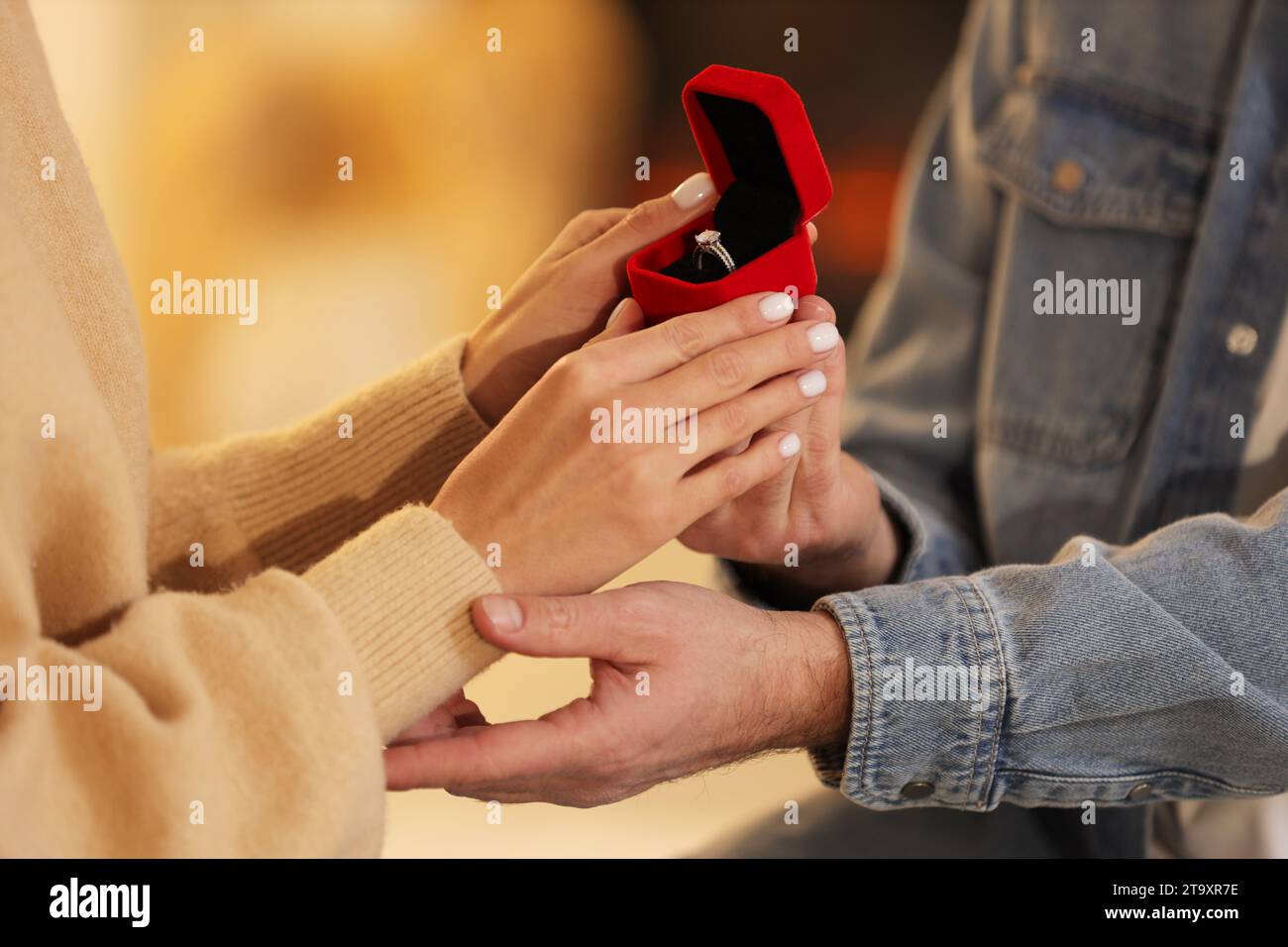 Man with engagement ring making proposal to his girlfriend against blurred background, closeup Stock Photo