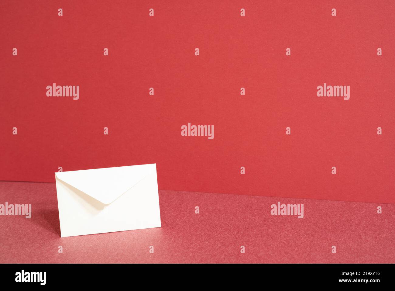 White paper envelope on red table. red wall background Stock Photo