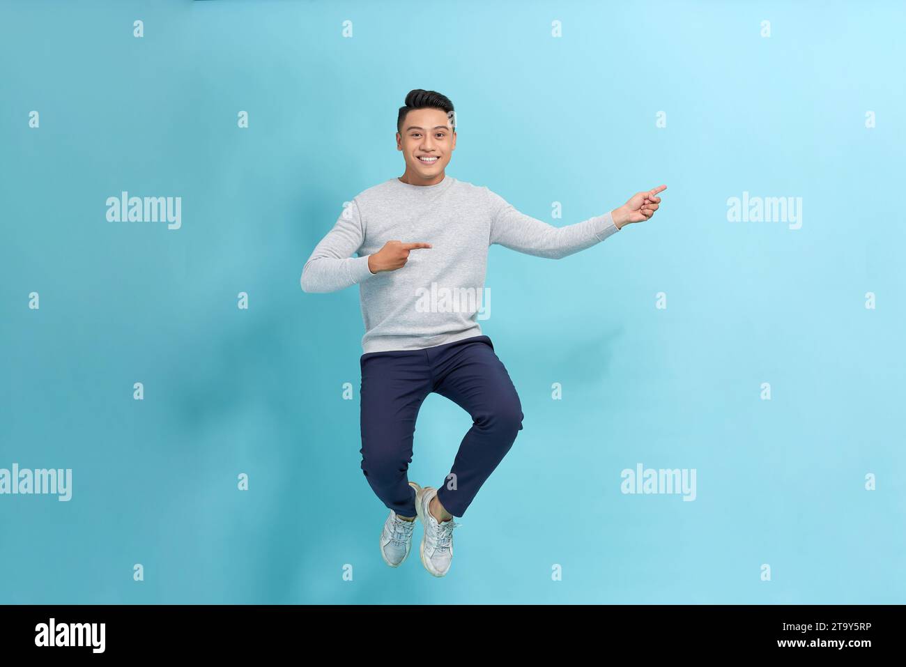 Photo of emotional excited young man jumping isolated, showing thumbs ...