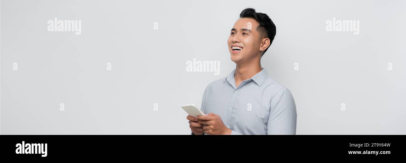 Smiling young good looking Asian man using smartphone isolated on white ...