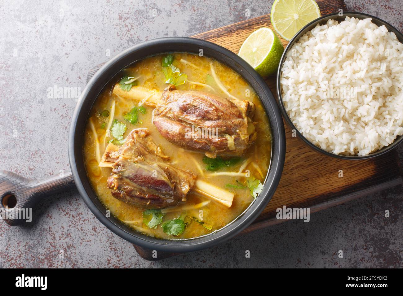 Lamb nihari, pakistani curry cuisine with garnish rice closeup on the wooden board on the table. Horizontal top view from above Stock Photo