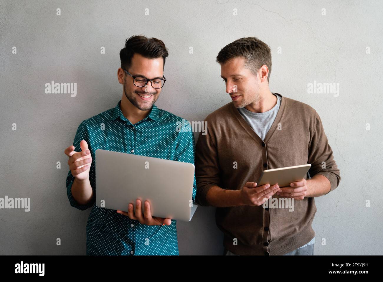 Young manager talking with experienced colleague while using computer in office. Stock Photo