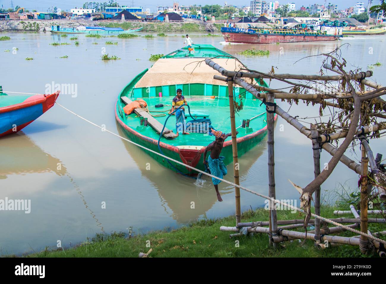 Traditional cargo boat station beside the riverbank. A picturesque scene unfolds along the riverbanks of Bangladesh as traditional cargo boats find th Stock Photo