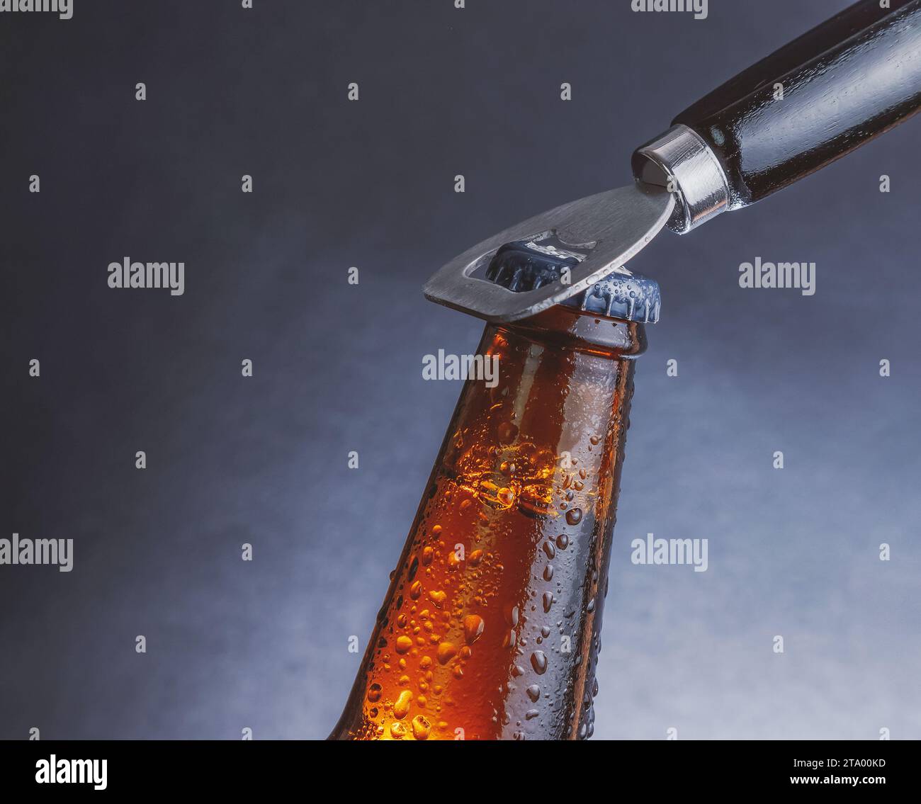 fresh cold beer ale bottle with drops and stopper open with bottle opener on dark background Stock Photo