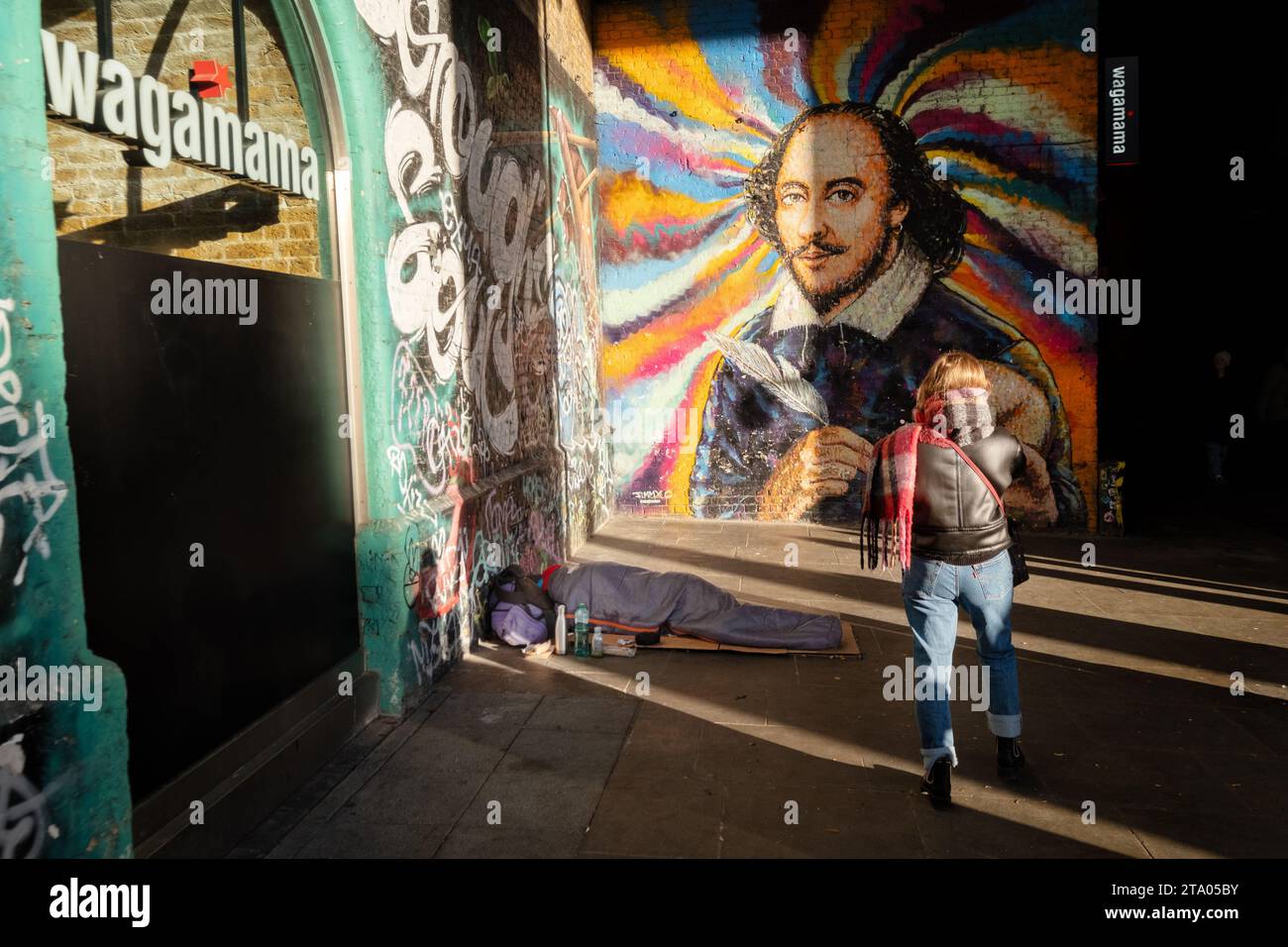 A tourist photographing a large mural of William Shakespeare on London's Southbank. The artwork is to the side of a Wagamama restaurant Stock Photo