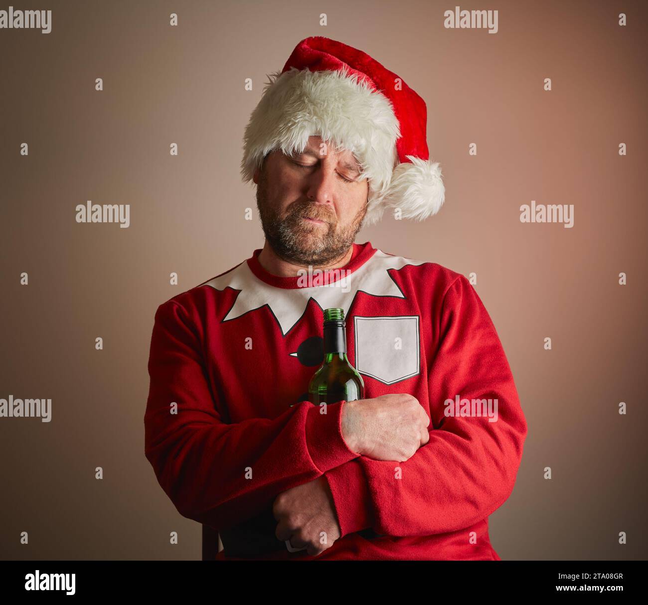 Man dressed as Santa who has fell asleep holding a bottle of wine with a gradient background. model release available. Stock Photo