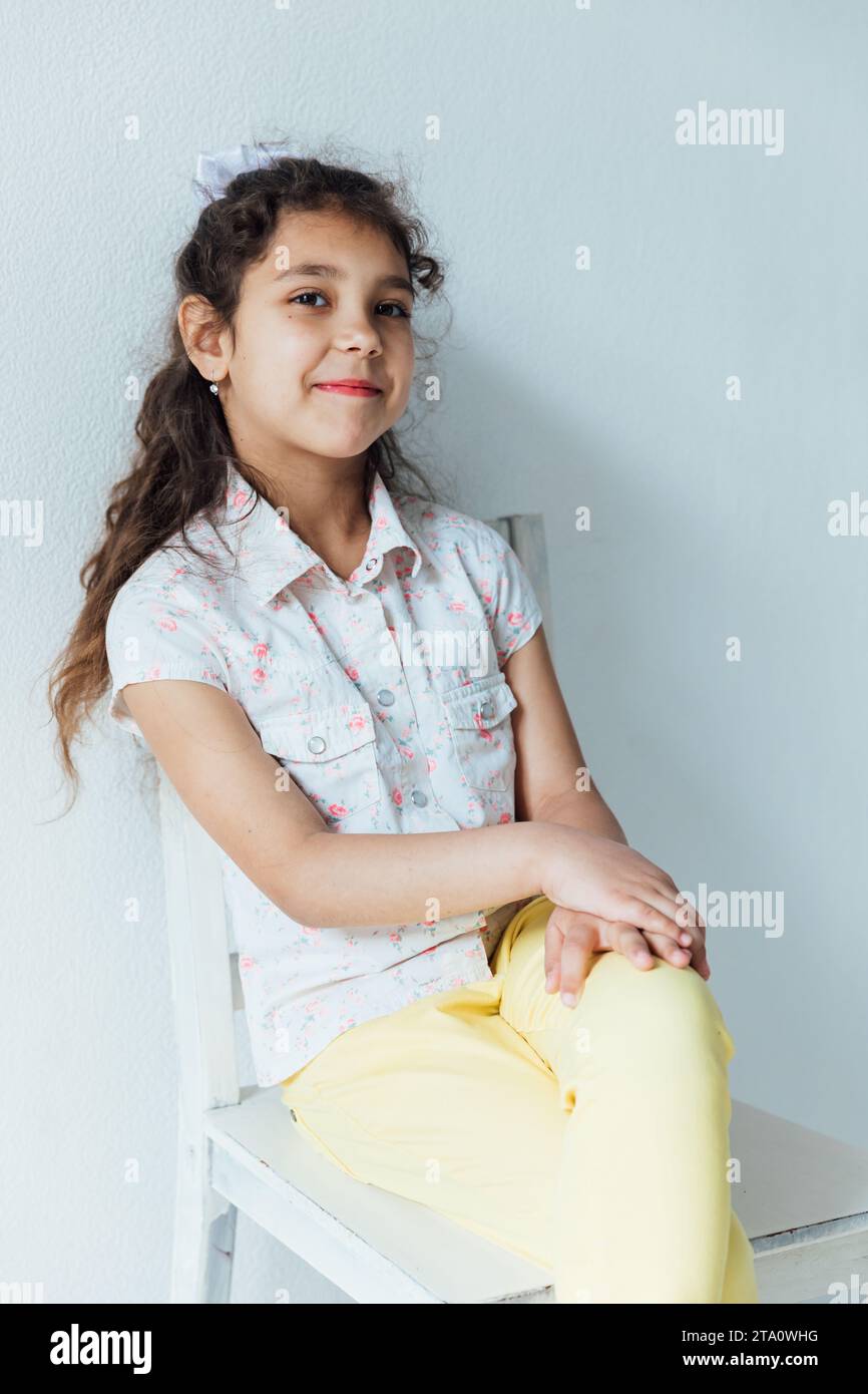 Beautiful little girl with curly hair sitting on a chair Stock Photo ...