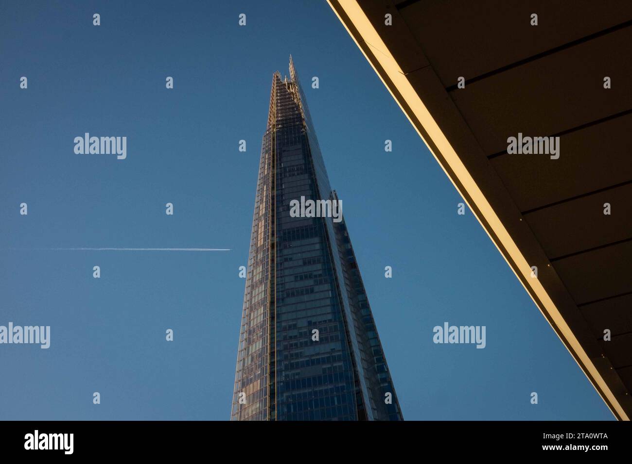 Looking up at The Shard, London, the tallest building in Britain with vapour trail of high flying jet going across sky. Stock Photo