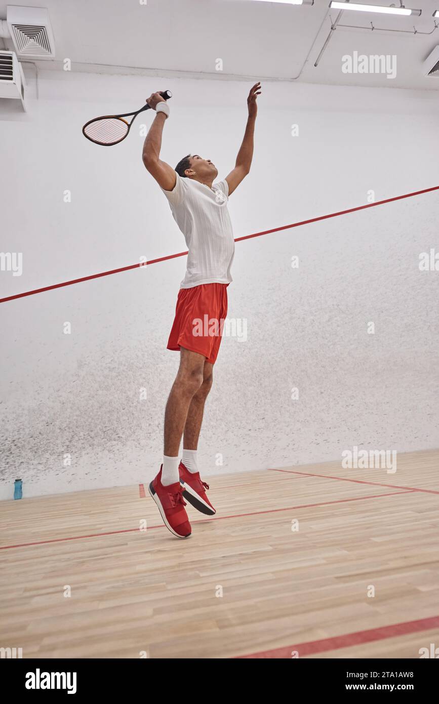 motion, energetic african american man holding racquet while jumping and playing squash, training Stock Photo