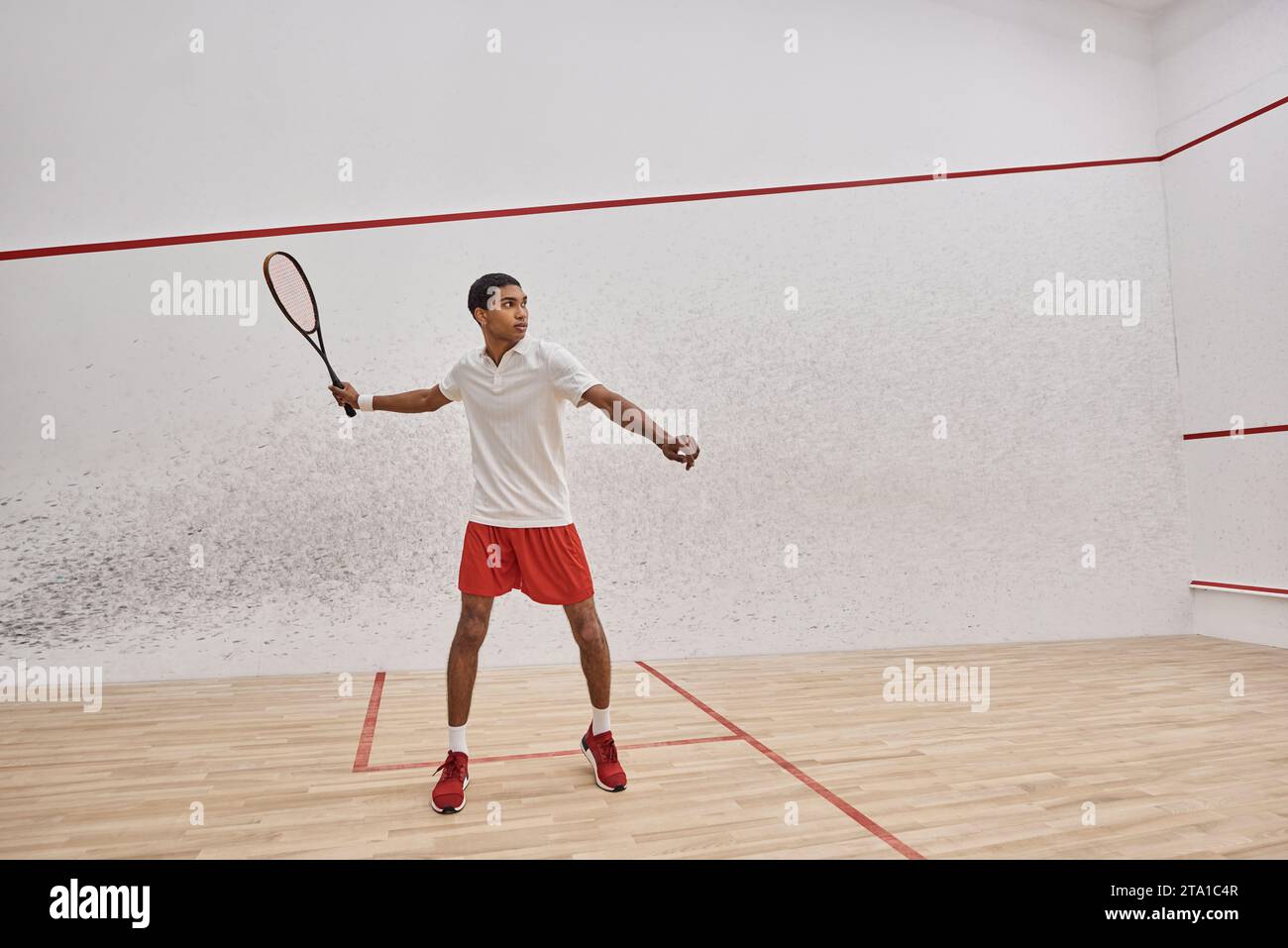 athletic african american man holding squash racquet and jumping while playing game in court Stock Photo