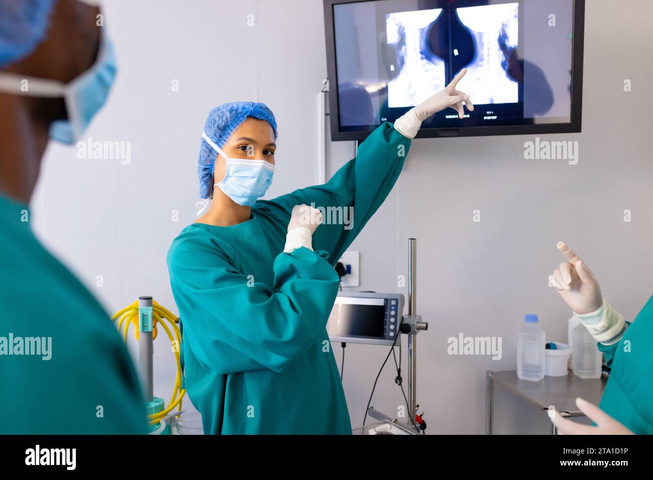 Diverse male and female surgeons with face masks looking at xrays in hospital operating room