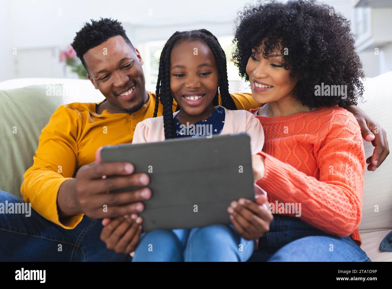 Happy african american family sitting on couch and using tablet at home ...