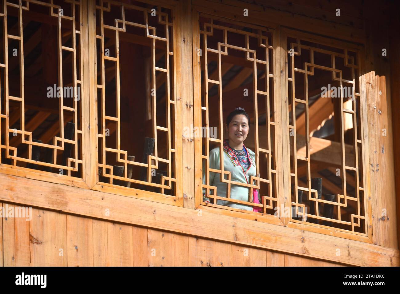 Rongshui. 28th Nov, 2023. A woman looks out of the window of a stilt building in Wuying Village on the border between south China's Guangxi Zhuang Autonomous Region and southwest China's Guizhou Province, Oct, 4, 2023. Wuying Village is a Miao ethnic group hamlet that nestles snugly in the towering mountains stretching across the border between Guangxi and Guizhou. Most villagers are still living in traditional wood stilt buildings. Credit: Huang Xiaobang/Xinhua/Alamy Live News Stock Photo