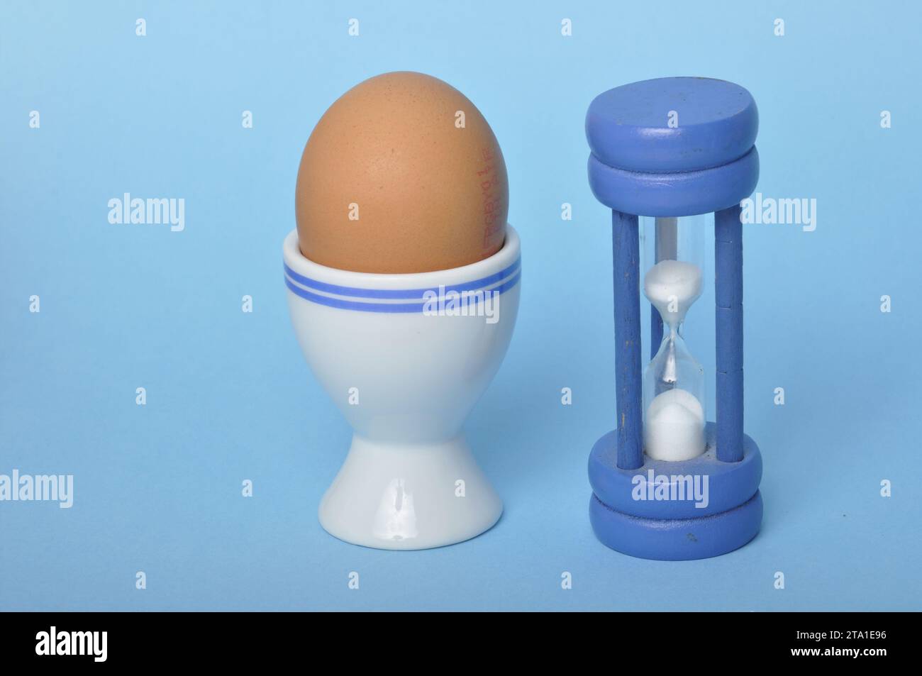 Boiled egg and hourglass on a blue background Stock Photo