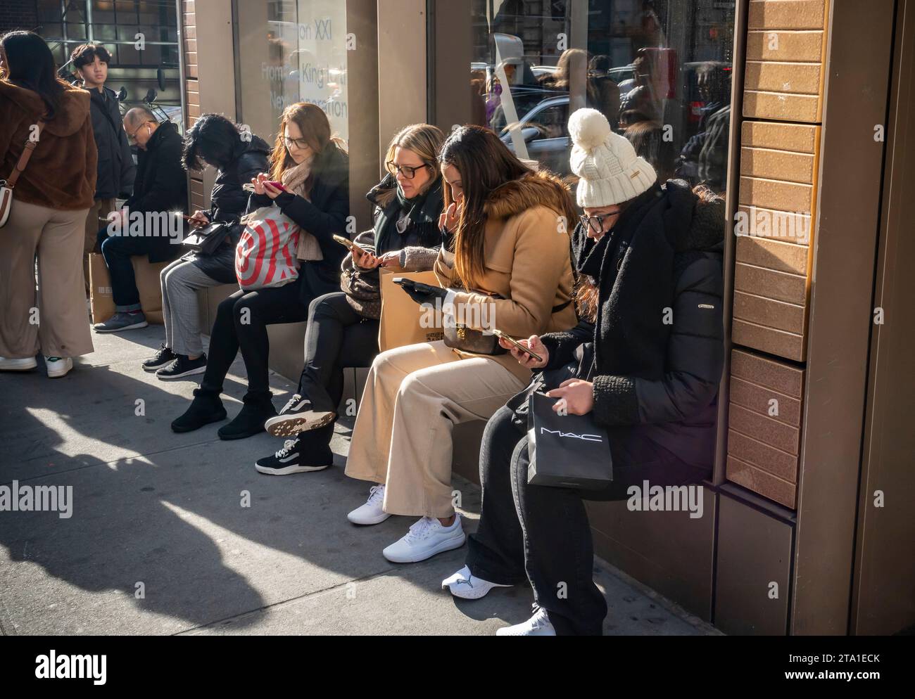 Shoppers engaged with their smartphones in the Soho neighborhood of New York on Saturday, November 25, 2023 during the Black Friday weekend.The National Retail Federation predicts 182 million people will shop over the Black Friday weekend, both in-person and online, culminating in Cyber Monday. (© Richard B. Levine) Stock Photo