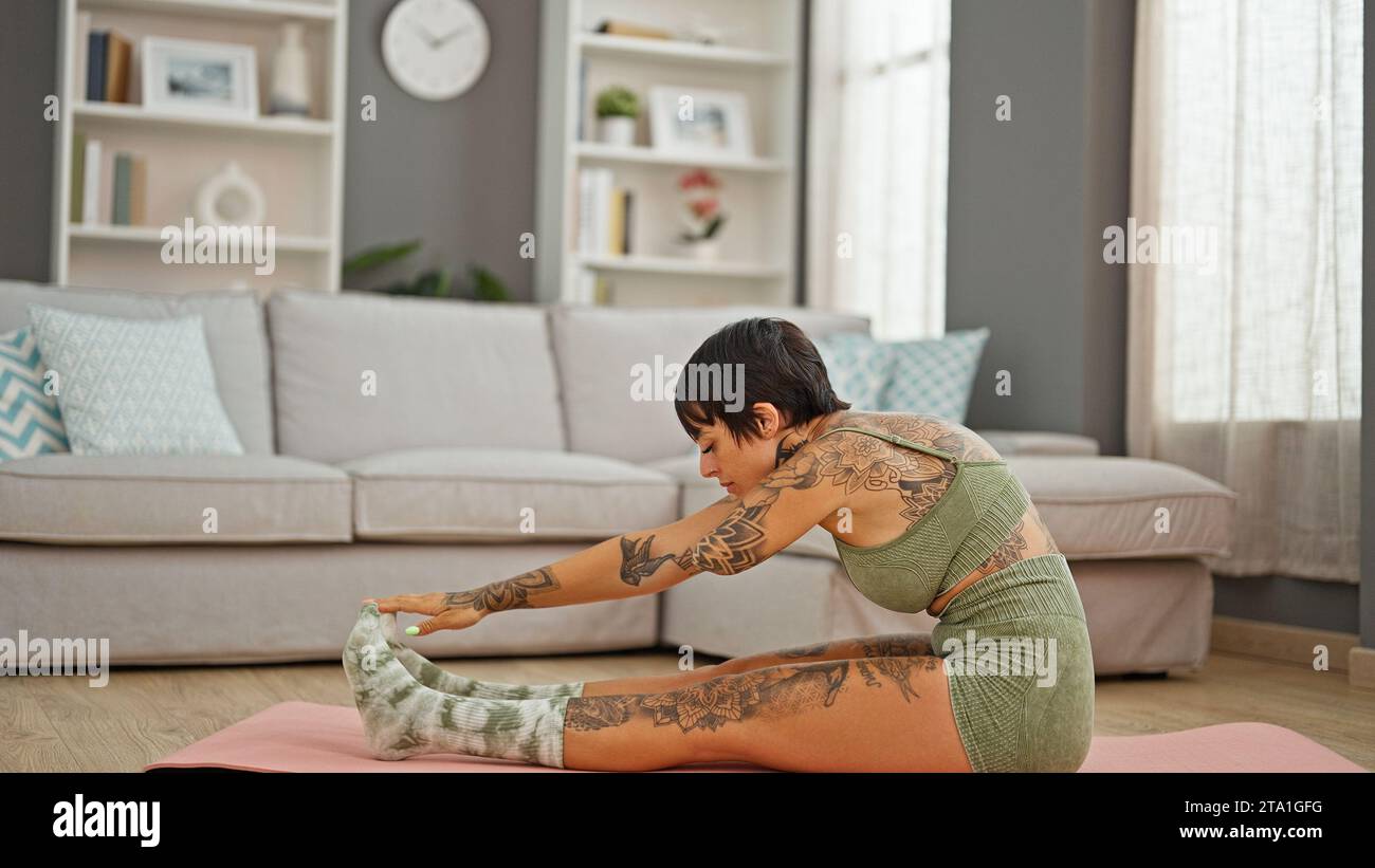 Hispanic woman with amputee arm sitting on floor stretching legs at ...