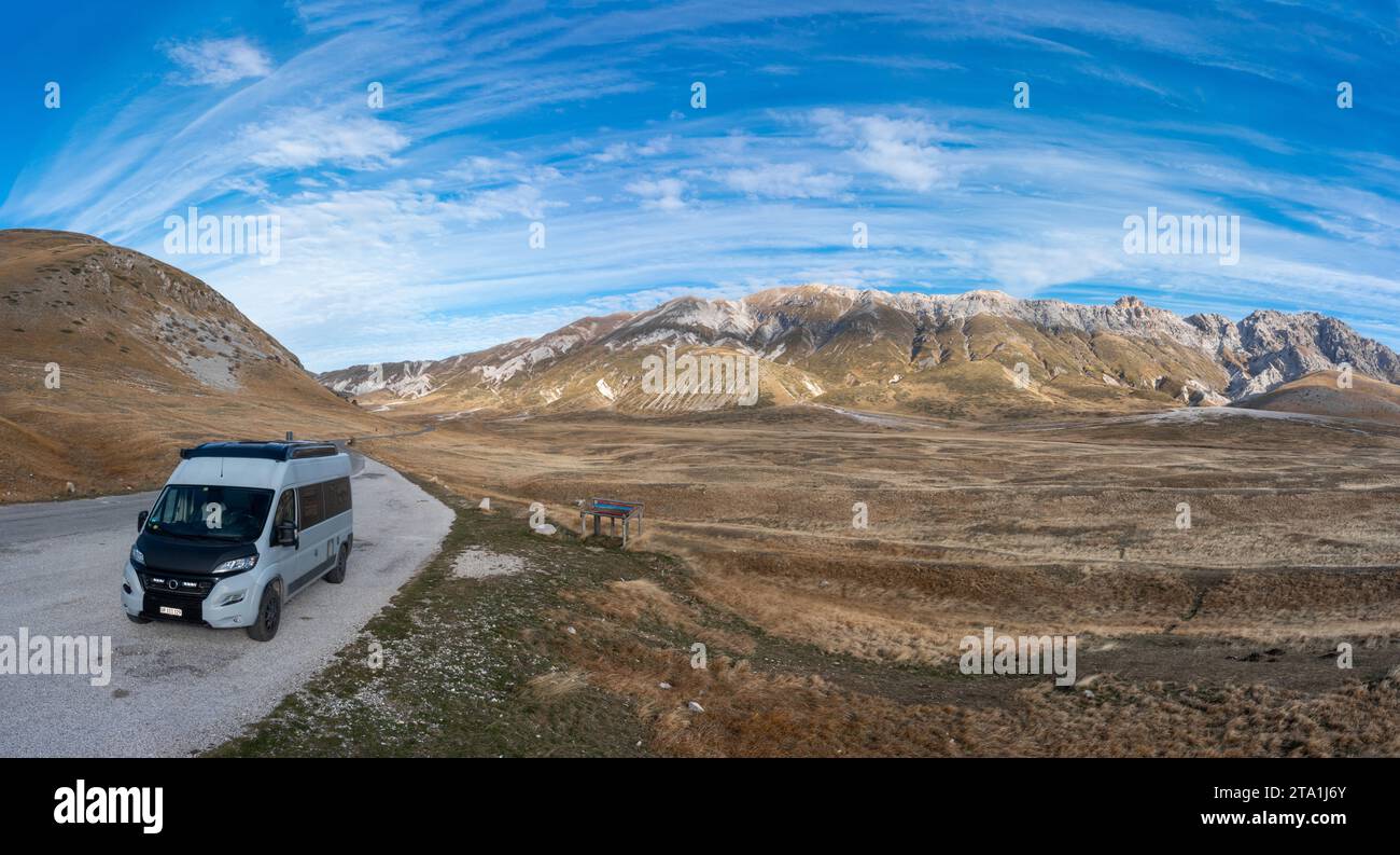 drone panorama landscape of Little Tibet in the Gran Sasso and Monti della Laga National Park in Abruzzo with a camper van in the foreground Stock Photo