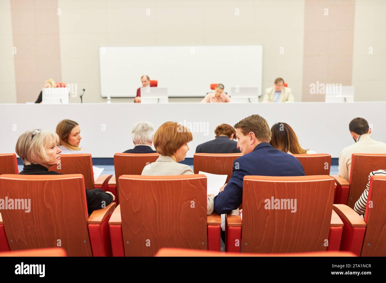 Male and female professionals sitting at audience in front of panel