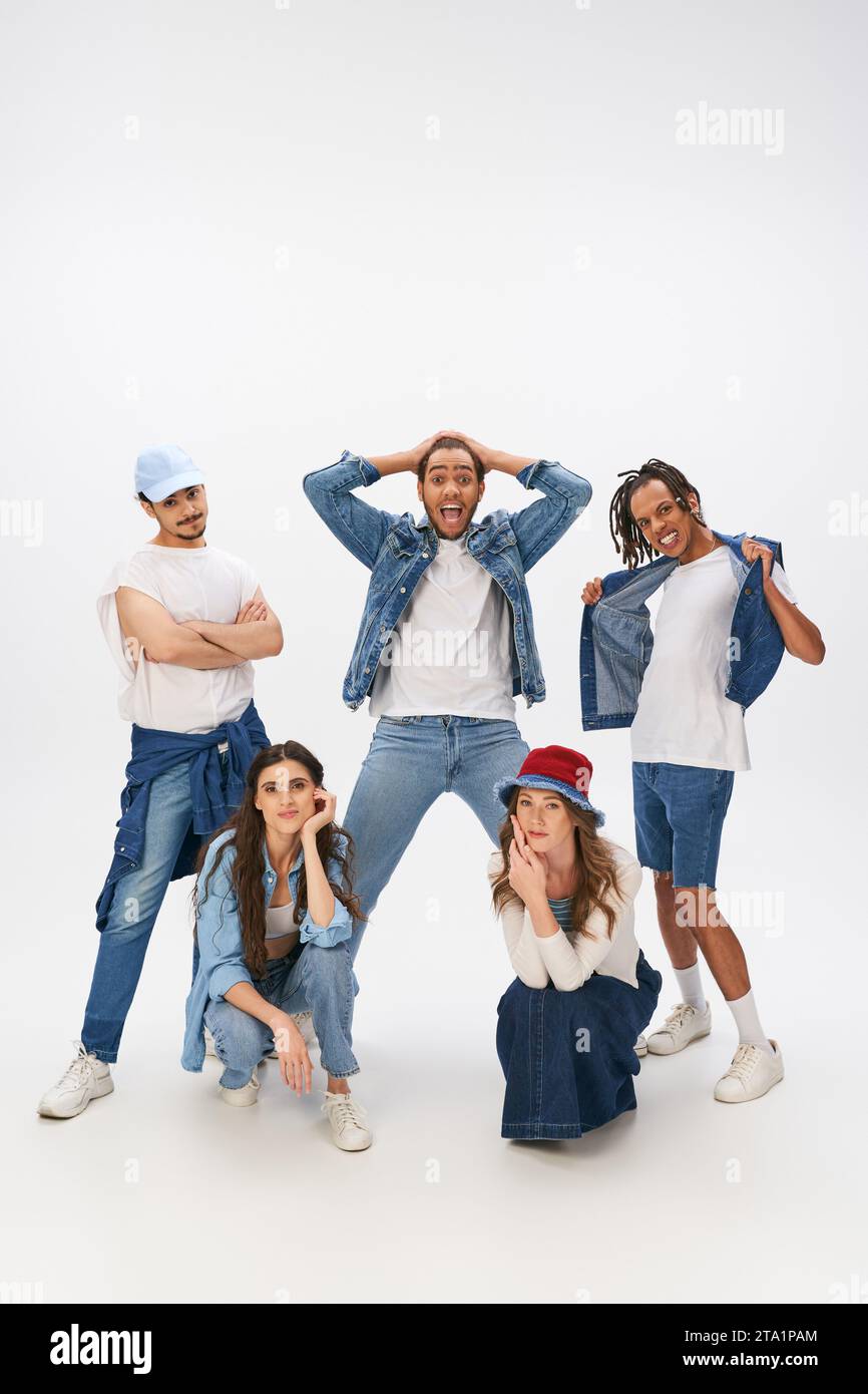 excited multicultural men posing near stylish women squatting on grey ...