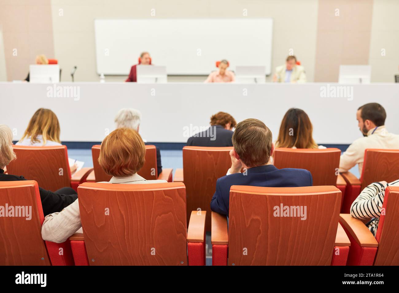 Male and female professionals sitting at audience in front of panel