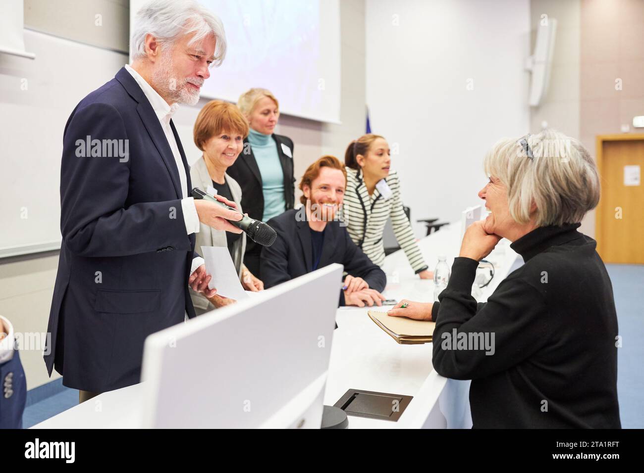Speaker holding microphone discussing with woman at panel during event ...