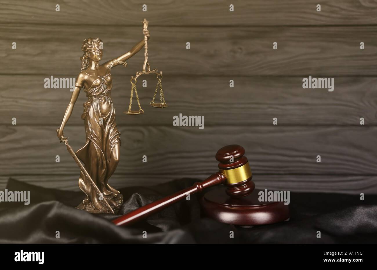 The Statue of Justice - lady justice or justitia the Roman goddess of Justice. Statue on brown book with judge gavel. Concept of judicial trial, courtroom process and lawyers occupation Stock Photo