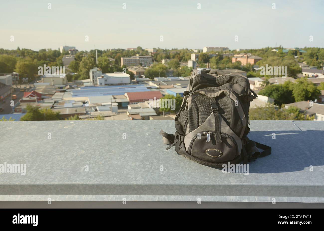 Black backpack lies on metal border of residental multistorey building ...