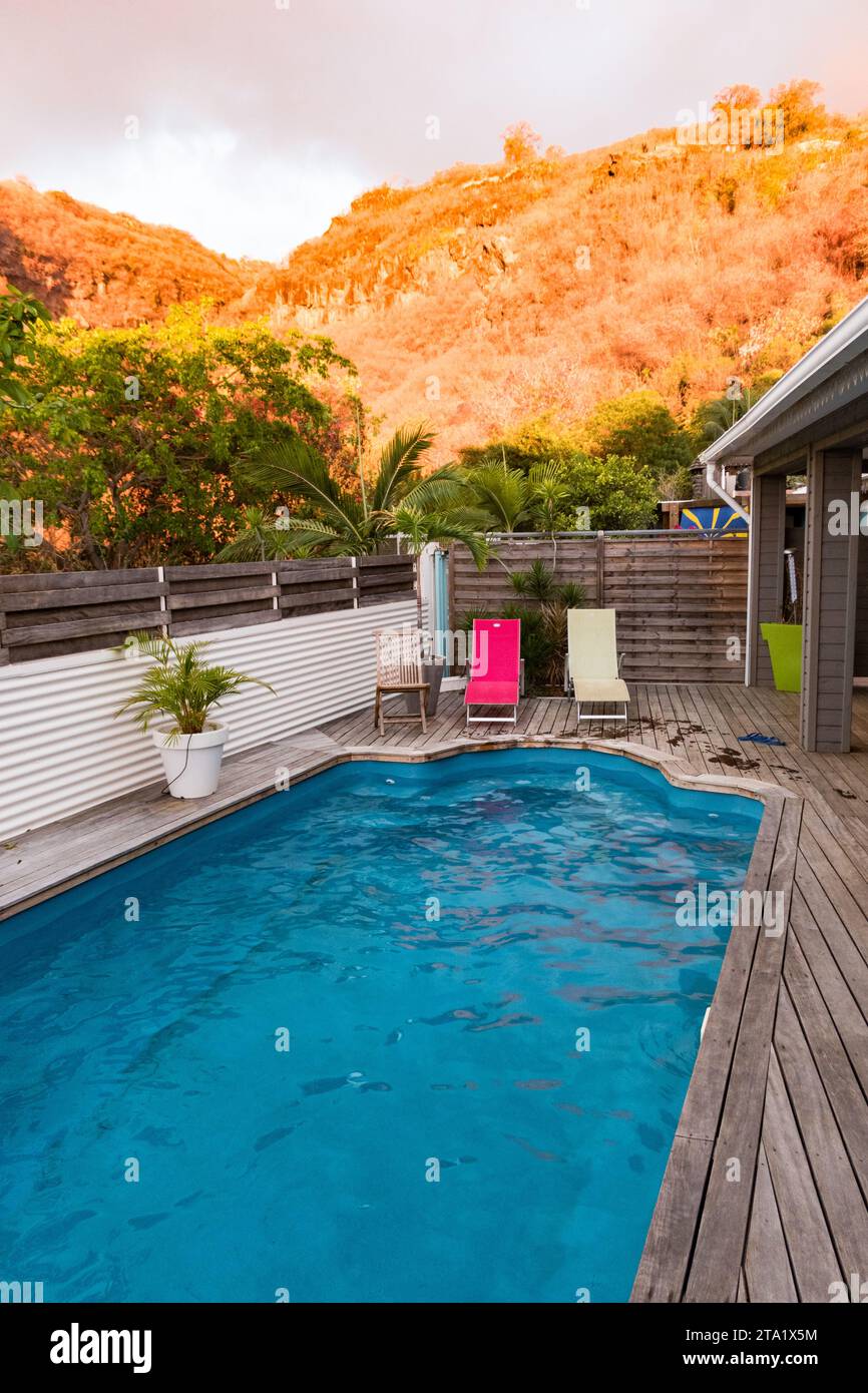 Two deck chairs, fuchsia and white, at sunset by a swimming pool, St-Leu, Reunion Island, France. Stock Photo