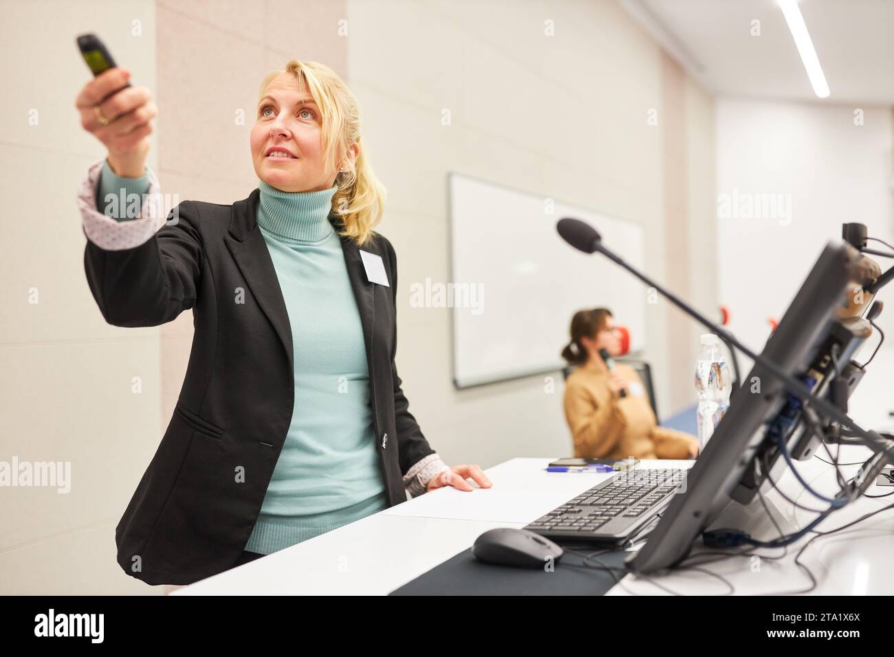Female speaker using remote control while giving presentation at