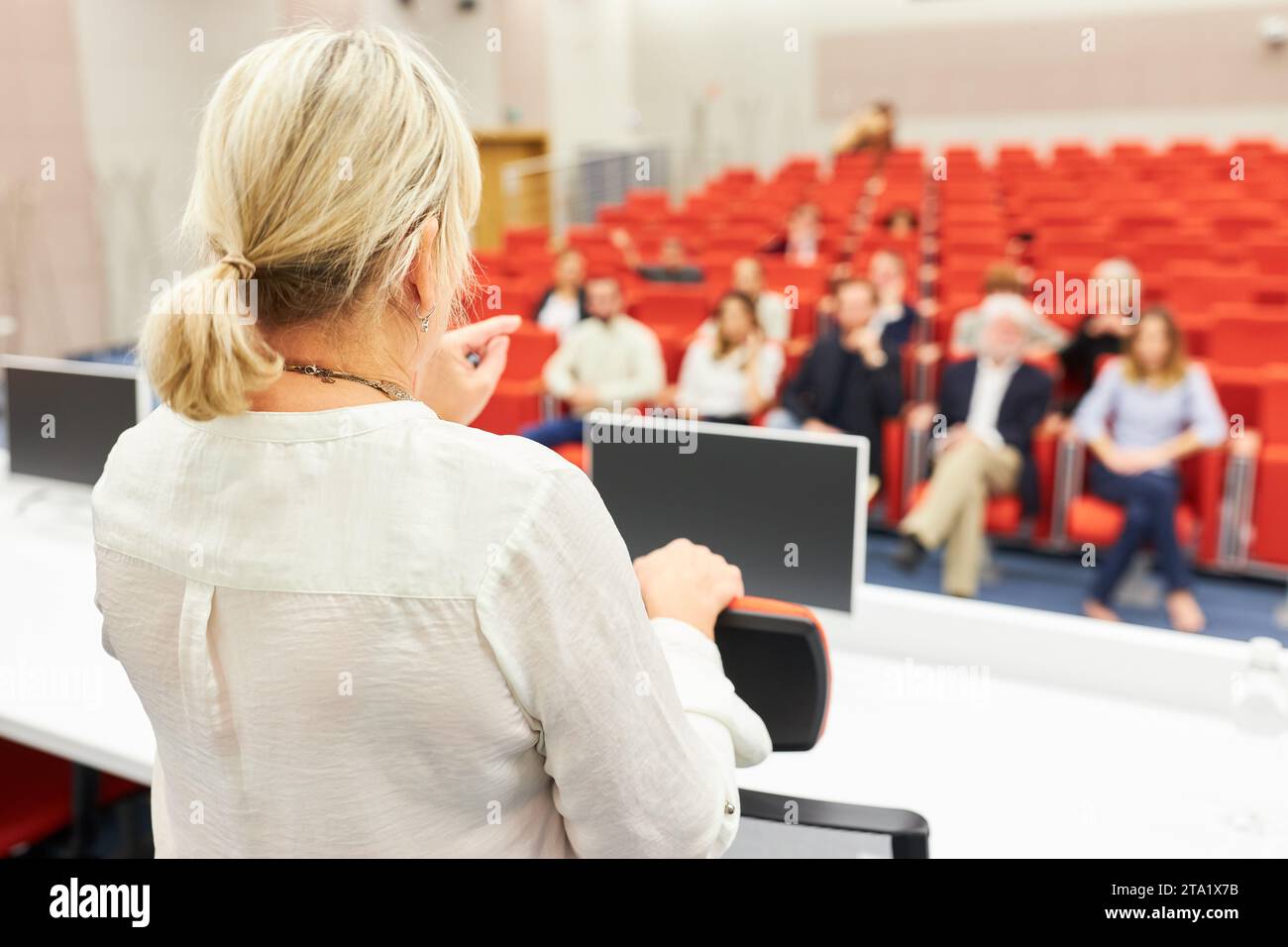 Rear view of female speaker explaining audience while giving speech in ...