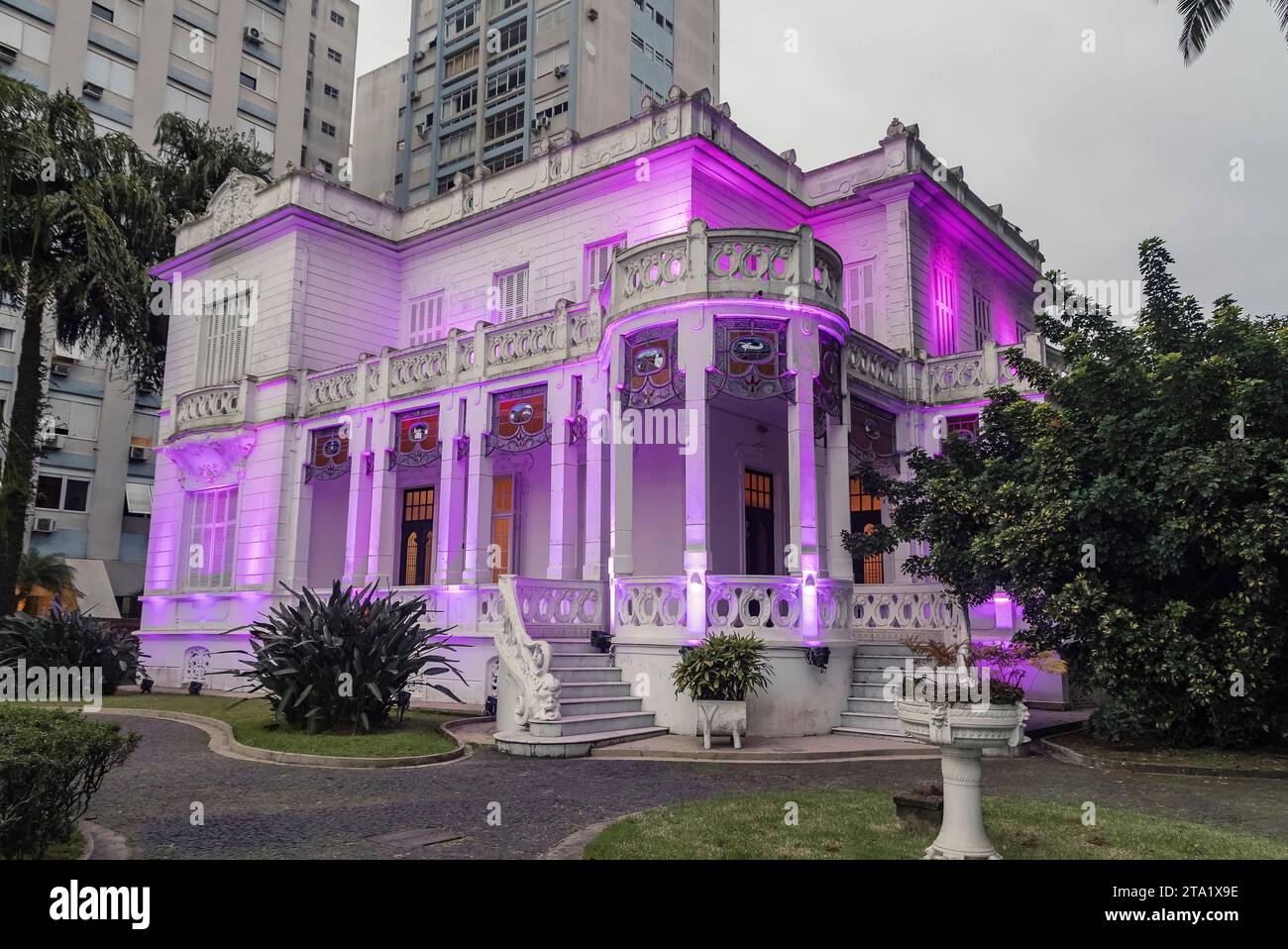 Santos city, Brazil. Old mansion and garden on the edge of the city and headquarters illuminated in purple at the end of the afternoon. Stock Photo