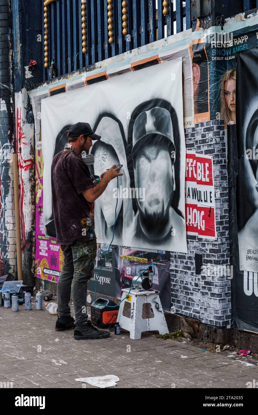 London, UK - August 25, 2023: Artist painting graffiti on the wall in Brick Lane in Shoreditch in the East End Stock Photo