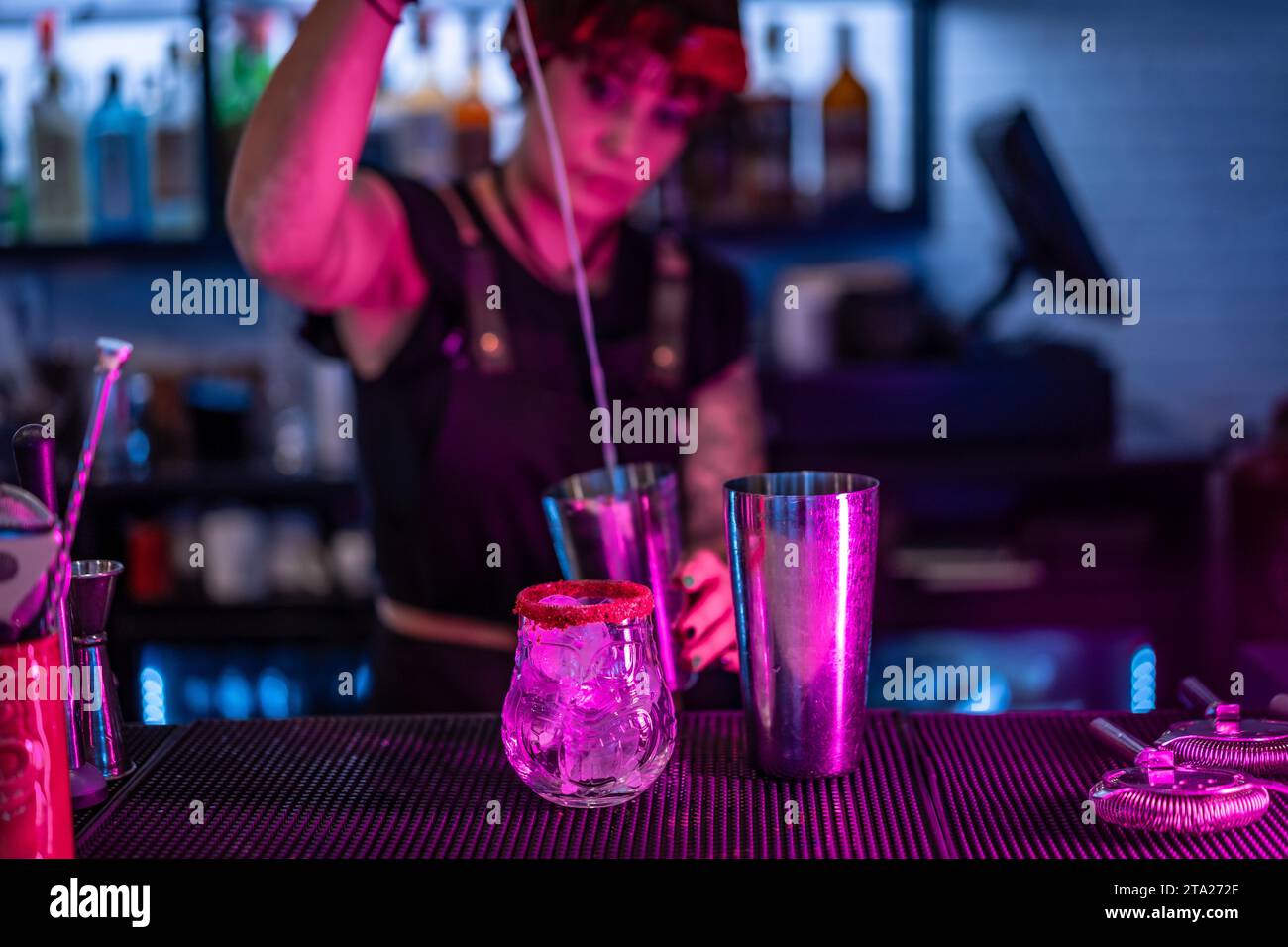 Bartender pouring alcohol to a mixer preparing a cocktail in the