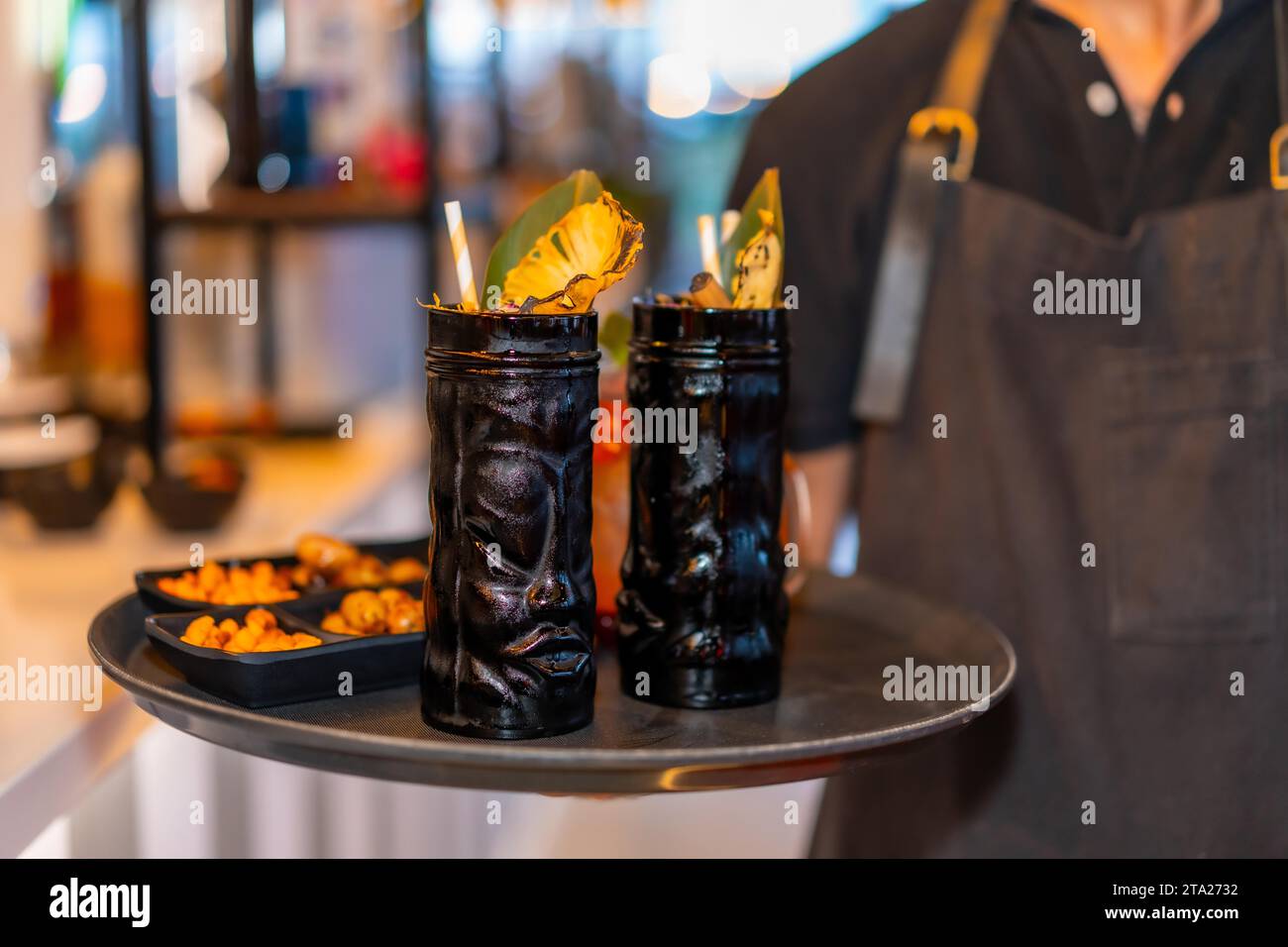 Bartender serving two cocktails in dark glasses in a plate in a night bar Stock Photo