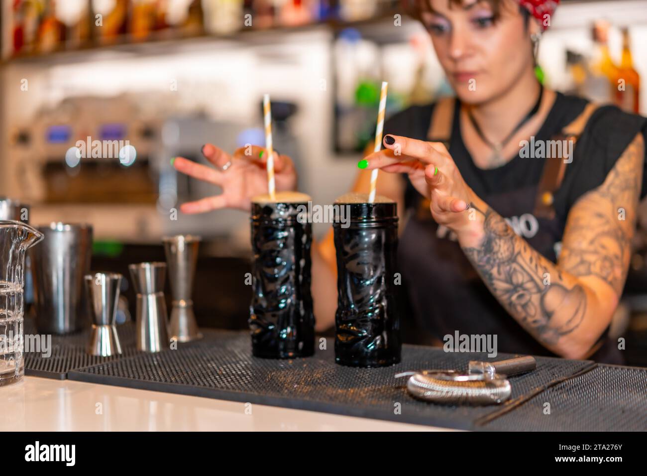 Bartender with two cocktails with straws ready to serve in the counter